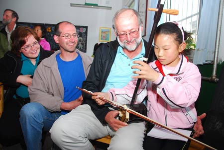  A pupil shows Canadian kite lovers how to play Erhu, a traditional Chinese musical instrument, at Xingfujie Primary School in Weifang, east China's Shandong Province, April 23, 2009. Canadian participants of the 26th International Kite Festival were invited to the school for cultural exchanges with pupils Thursday. [Wang Lijun/Xinhua] 