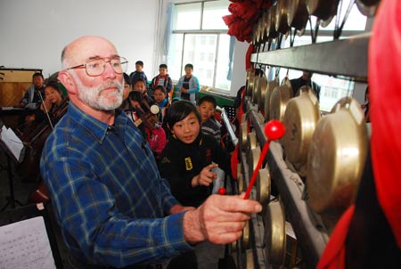 A Canadian kite lover learns to beat Yunluo, a kind of Chinese musical instrument, at Xingfujie Primary School in Weifang, east China's Shandong Province, April 23, 2009. Canadian participants of the 26th International Kite Festival were invited to the school for cultural exchanges with pupils Thursday. [Wang Lijun/Xinhua]