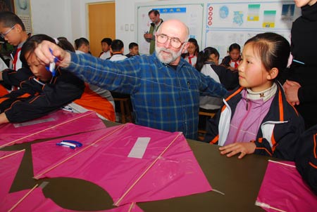 A Canadian kite lover teaches pupils to make Canadian-style kites at Xingfujie Primary School in Weifang, east China's Shandong Province, April 23, 2009. Canadian participants of the 26th International Kite Festival were invited to the school for cultural exchanges with pupils Thursday.[Xinhua]