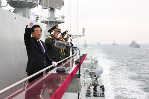 Chinese President Hu Jintao (L) waves to the navy vessels which are being reviewed while aboard the destroyer Shijiazhuang in waters off Qingdao, east China's Shandong Province, April 23, 2009. A parade displayed 25 naval vessels and 31 aircrafts of the PLA Navy, including two nuclear submarines, as part of a celebration to mark the 60th anniversary of the founding of the PLA Navy.[Xinhua]