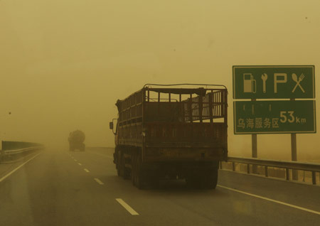 Vehicles run in sandstorm on a highway in Inner Mongolia Autonomous Region, north China, April 23, 2009. The heavy sandstorm caused inconvenience for local production and traffic on Thursday. [Xinhua]