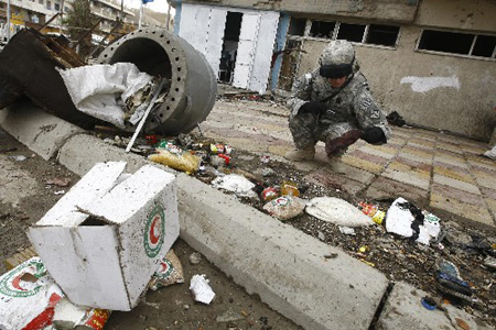 A soldier investigates the site of a suicide bombing in Baghdad April 23, 2009. A suicide bomber wearing a vest stuffed with explosives blew himself up in a group of police distributing relief supplies in Baghdad on Thursday, killing at least 28 people and wounding 50, Iraqi police said. [Xinhua/Reuters]