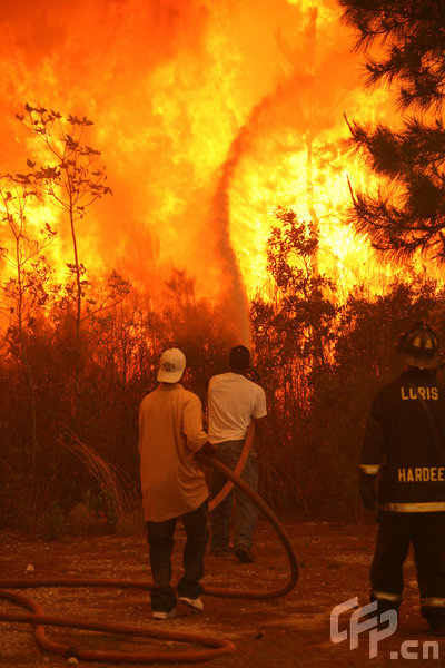  Two men spray water on a raging fire as it threatens nearby homes on April 23, 2009 near Conway, South Carolina. South Carolina Gov. Mark Sanford declared a state of emergency Thursday for a coastal county where a wildfire has consumed thousands of acres and destroyed dozens of homes.[Logan Mock-Bunting/GettyNorthAmerica/CFP]