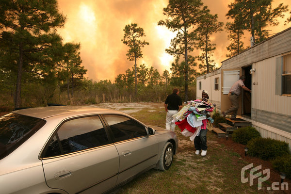 Men try to salvage belongings as a wildfire advances towards homes on April 23, 2009 near Conway, South Carolina. South Carolina Gov. Mark Sanford declared a state of emergency Thursday for a coastal county where a wildfire has consumed thousands of acres and destroyed dozens of homes. [Logan Mock-Bunting/GettyNorthAmerica/CFP]