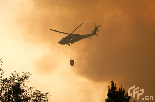 A helicopter brings water to fight a wildfire threatening homes on April 23, 2009 near Conway, South Carolina. South Carolina Gov. Mark Sanford declared a state of emergency Thursday for a coastal county where a wildfire has consumed thousands of acres and destroyed dozens of homes.[Logan Mock-Bunting/GettyNorthAmerica/CFP]