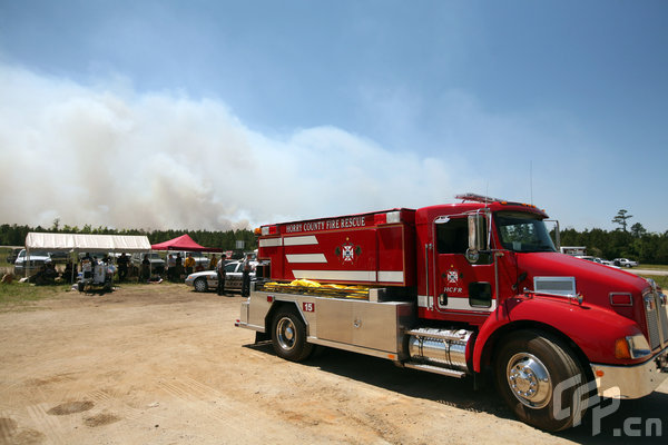 Fire and police forces work on scene as a wildfire rages nearby threatening homes on April 23, 2009 near Myrtle Beach, South Carolina. South Carolina Gov. Mark Sanford declared a state of emergency Thursday for a coastal county where a wildfire has consumed thousands of acres and destroyed dozens of homes. [Logan Mock-Bunting/GettyNorthAmerica/CFP]