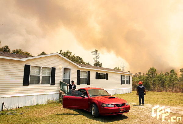 A woman prepares to evacuate her home as a wildfire rages nearby on April 23, 2009 near Myrtle Beach, South Carolina. South Carolina Gov. Mark Sanford declared a state of emergency Thursday for a coastal county where a wildfire has consumed thousands of acres and destroyed dozens of homes. [Logan Mock-Bunting/GettyNorthAmerica/CFP]