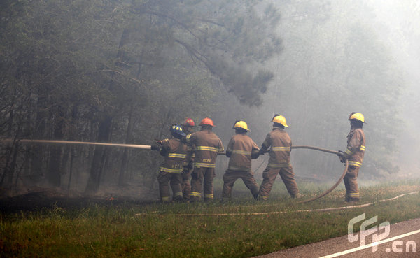 Firefighters with Horry County Fire and Rescue work to keep a fire down after it crossed Highway 22 in rural Horry County, South Carolina on Thursday, April 23, 2009. [Logan Mock-Bunting/GettyNorthAmerica/CFP]