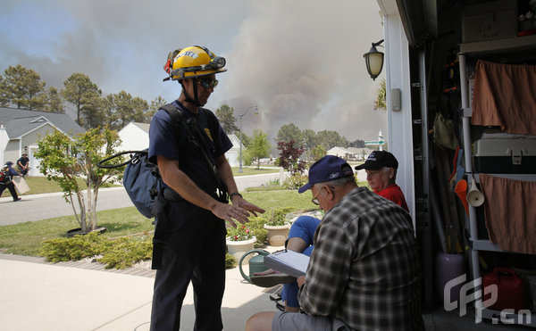 George and Christel Hoskins talk with Myrtle Beach Fire Department Lt. Bob Horn outside the Hoskins' home on Thursday, April 23, 2009, in North Myrtle Beach, South Carolina.[Logan Mock-Bunting/GettyNorthAmerica/CFP]