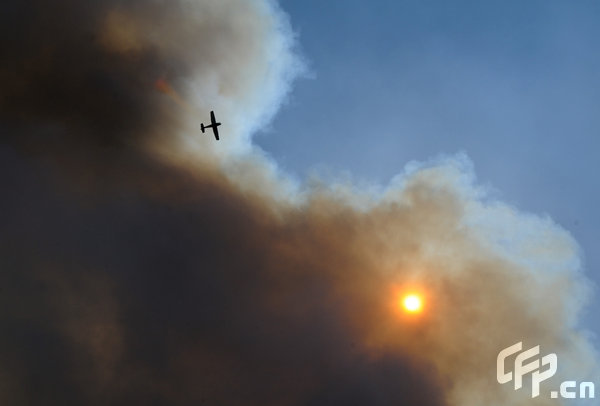 A plane circle a wildfire burning near North Myrtle Beach, South Carolina on Thursday, April 23, 2009. [Logan Mock-Bunting/GettyNorthAmerica/CFP] 