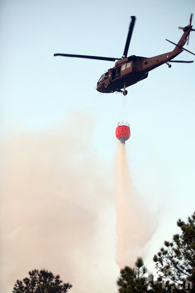 A helicopter drops water on wildfires near homes on April 23, 2009 in Conway, South Carolina. Gov. Mark Sanford declared a state of emergency today for the coastal are where the blaze has consumed thousands of acres and destroyed dozens of homes. [Logan Mock-Bunting/GettyNorthAmerica/CFP]