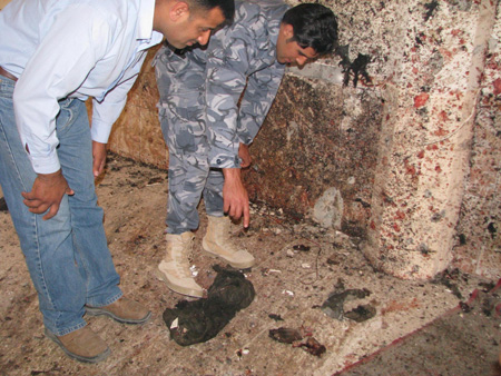 Two Iraqi policemen inspect a suicide bomb scene in Duloiyah, Salahuddin, Iraq, April 23, 2009. A suicide bomber, around 20 years old, blew himself up in a local mosque, claiming the lives of four prayers and wounding ten others. (Xinhua/Shaalan Jubury)