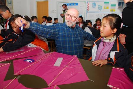 A Canadian kite lover teaches pupils to make Canadian-style kites at Xingfujie Primary School in Weifang, east China's Shandong Province, April 23, 2009. Canadian participants of the 26th International Kite Festival were invited to the school for cultural exchanges with pupils Thursday. [Wang Lijun/Xinhua]