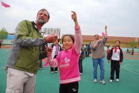 Canadian kite lovers fly kites with pupils at Xingfujie Primary School in Weifang, east China's Shandong Province, April 23, 2009. Canadian participants of the 26th International Kite Festival were invited to the school for cultural exchanges with pupils Thursday. [Wang Lijun/Xinhua]