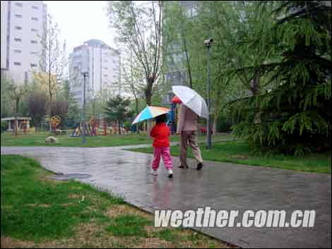 People walk in the rain in Beijing on the morning of April 23, 2009. Influenced by the cold and humid airflow heading south, the capital is enjoying welcome rain after a prolonged spell of drought, according to www.weather.com.cn. 