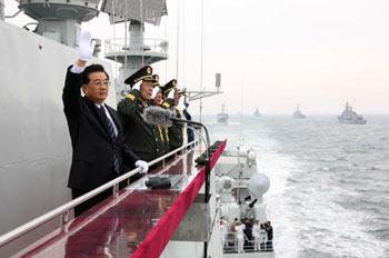 Chinese President Hu Jintao (L) waves to the navy vessels which are being reviewed while aboard the destroyer Shijiazhuang in waters off Qingdao, east China&apos;s Shandong Province, April 23, 2009. A parade displayed 25 naval vessels and 31 aircrafts of the PLA Navy, including two nuclear submarines, as part of a celebration to mark the 60th anniversary of the founding of the PLA Navy.[Wang Jianmin/Xinhua] 