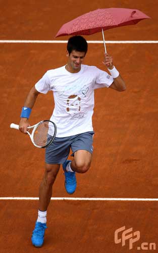 Novak Djorkovic of Serbia plays tennis with an umbrella in a charity match with Andreas Seppi of Italy in memory of Luzzi Federico of Italy who died with leukemia last year during previews for the Foro Italico Tennis Masters on April 26, 2009 in Rome, Italy.