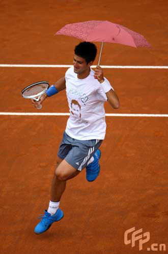 Novak Djorkovic of Serbia plays tennis with an umbrella in a charity match with Andreas Seppi of Italy in memory of Luzzi Federico of Italy who died with leukemia last year during previews for the Foro Italico Tennis Masters on April 26, 2009 in Rome, Italy.