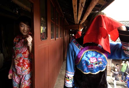 A tourist (L) is dressed up as a bride by local villagers of Tujia ethnic group as she experiences the local marriage traditions at a tourist destination in Jiangkou County, southwest China's Guizhou Province, April 25, 2009.