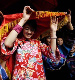 A tourist is dressed up as a bride by local villagers of Tujia ethnic group as she experiences the local marriage traditions at a tourist destination in Jiangkou County, southwest China's Guizhou Province, April 25, 2009. 