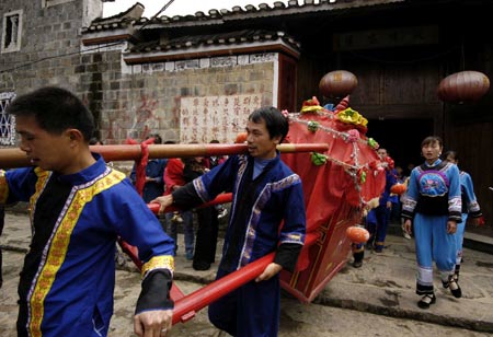 Local villagers of Tujia ethnic group carry a bride in a sedan as they show off local marriage traditions at a tourist destination in Jiangkou County, southwest China's Guizhou Province, April 25, 2009.