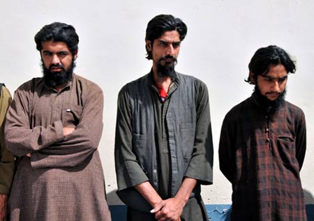 Three of the seven arrested Taliban members stands in front of a wall in Helmand province, southern Afghanistan, April 25, 2009.