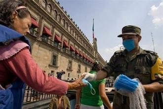 A soldier hands out masks outside the National Palace in Mexico City. [Alfredo Estrella/CCTV/AFP] 