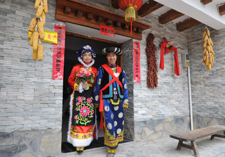 Bridegroom Tang Zhiguo (R) and his bride walk to attend wedding at the Jina Qiang Ethnic Minority Village of Beichuan County, southwest China's Sichuan Province, April 26, 2009. Twenty new couples held group wedding here on Sunday. [He Junchang/Xinhua] 