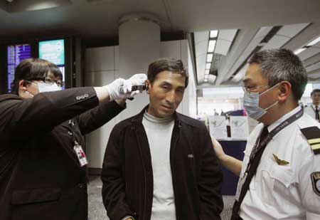  Staff members check the temperature of a passenger at Hong Kong International Airport in Hong Kong, south China, April 27, 2009. Hong Kong Special Administrative Region has taken measures to contain the possible spread of swine flu.