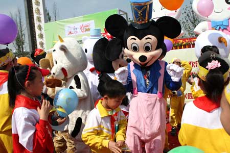 Cartoon star Mickey Mouse plays with children in a scenic spot of Nantong Horticulture Expo Park in Nantong, a city of east China's Jiangsu Province, April 27, 2009. [Photo:Xinhua]