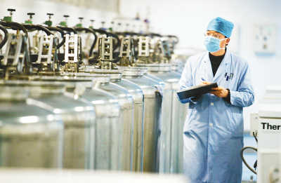 A researcher from Tianjin Cord-Blood Bank examines liquid nitrogen cans used to store umbilical cord-blood units. [People's Daily]