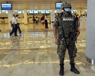 A Mexican soldier wears a surgical mask as he stands guard at Mexico City's international airport Benito Juarez April 27, 2009. [Felipe Leon /REUTERS]