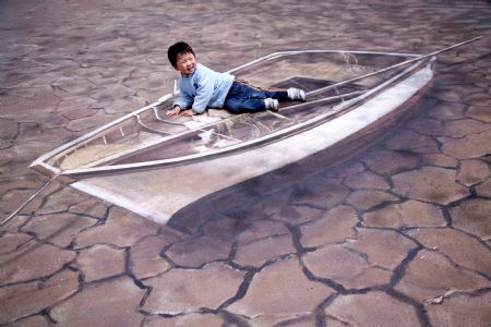 A kid poses for a photo on a cubic drawing displayed at the Xuanwuhu Park in Nanjing, capital of east China's Jiangsu Province, April 25, 2009. More than 30 such pictures are displayed here recently, a strong cubic effect of which can be seen from a certain angle. [Xinhua/Wang Xin]