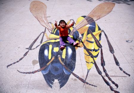 A kid poses for a photo on a cubic drawing displayed at the Xuanwuhu Park in Nanjing, capital of east China's Jiangsu Province, April 25, 2009. More than 30 such pictures are displayed here recently, a strong cubic effect of which can be seen from a certain angle. [Xinhua/Wang Xin] 
