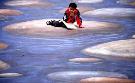 A kid poses for a photo on a cubic drawing displayed at the Xuanwuhu Park in Nanjing, capital of east China&apos;s Jiangsu Province, April 25, 2009. More than 30 such pictures are displayed here recently, a strong cubic effect of which can be seen from a certain angle. [Xinhua/Wang Xin]