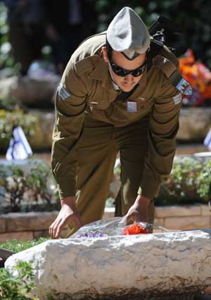 An Israeli soldier presents flowers to the grave of his relative at the Military Cemetery in Jerusalem, April 28, 2009.