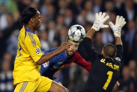 Barcelona's goalkeeper Victor Valdes (R) saves a shot from Chelsea's Didier Drogba (L) as Barcelona's Gerard Pique looks on during their Champions League semi-final, first leg soccer match in Barcelona April 28, 2009.