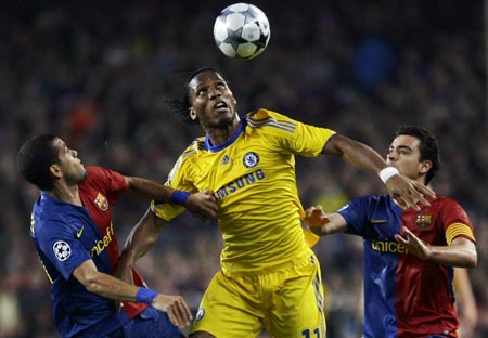 Chelsea's Didier Drogba (C) goes for a header between Barcelona's Daniel Alves (L) and Xavi during their Champions League semi-final, first leg soccer match in Barcelona April 28, 2009.