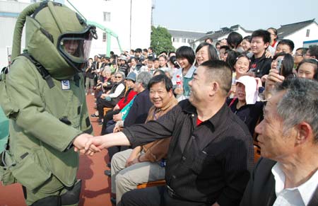 A citizen with explosive-proof on shakes hands with a local resident at an open day of local riot police in Suzhou, east China's Jiangsu Province April 28, 2009. Local police displayed police vehicles, weapons, shields, dogs and presented various skills to the citizens that day.