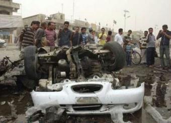 Residents gather at a burnt vehicle at the site of a bomb attack in Baghdad's Sadr City April 29, 2009. The toll from twin car bomb blasts on Wednesday in a busy market in Baghdad jumped to 41 killed and 68 wounded, Iraqi police said. [REUTERS/Kahtan al-Mesiary]