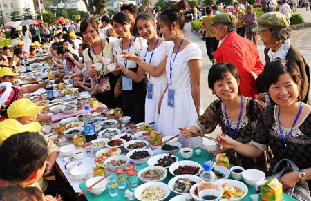Twins and tourists enjoy the feast during the 5th twin festival in the Hani Autonomous County of Mojiang, southwest China's Yunnan Province, May 2, 2009. A traditional Hani nationality feast on 2-kilometer-long table was held here on Saturday during the three-day twin festival with participation of nearly 1,000 pairs of twins and triplets. (Xinhua/Lin Yiguang)