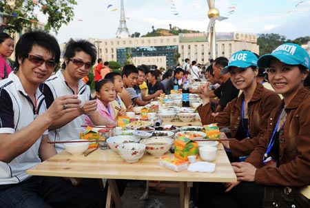 Twins and tourists enjoy the feast during the 5th twin festival in the Hani Autonomous County of Mojiang, southwest China's Yunnan Province, May 2, 2009. A traditional Hani nationality feast on 2-kilometer-long table was held here on Saturday during the three-day twin festival with participation of nearly 1,000 pairs of twins and triplets. (Xinhua/Lin Yiguang)