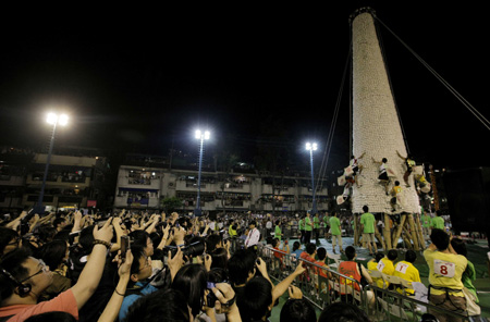 Spectators take photos as contestants participating in the Bun Scrambling-up Competition during Tai Ping Qing Jiao Festival on Cheung Chau island in Hong Kong, South China, May 2, 2009. The traditional Tai Ping Qing Jiao Festival was held as usual despite that the Hong Kong Government has raised the flu alert level from "serious" to the highest level of "emergency". The Tai Ping Qing Jiao Festival, also named the Bun Festival, is a combination of thanking gods for luck, praying to gods for safety and auspiciousness, furthermore, navigating the lost spirits. Parade, praying and bun scrambling-up competition are important events held during the festival. (Xinhua/Zhou Lei)