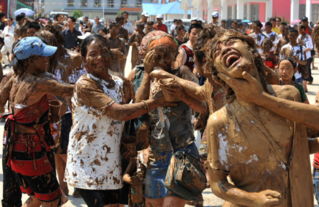 Tourists and the local Va ethnic people cover others with clay during a carnival at the Va Ethnic Autonomous Prefecture of Cangyuan, southwest China's Yunnan Province, May 2, 2009. During the 4-day festival, people daub each other with clay made of natural material, to express wishes of health and happiness. [Chen Haining/Xinhua] 