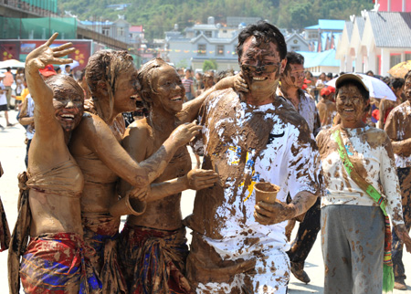 Tourists and the local Va ethnic people cover others with clay during a carnival at the Va Ethnic Autonomous Prefecture of Cangyuan, southwest China's Yunnan Province, May 2, 2009. [Chen Haining/Xinhua] 