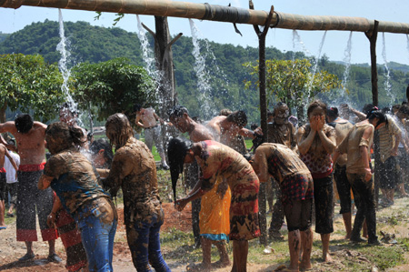 People covered with clay take a shower during a carnival at the Va Ethnic Autonomous Prefecture of Cangyuan, southwest China's Yunnan Province, May 2, 2009. [Chen Haining/Xinhua]