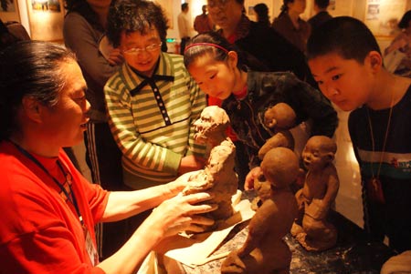 Li Yanping (L), a local noted folklorist specialized in the clay-sculpture, extemporizes his skillful finger-nipping of vivid figures, during an Improvisatori Performance of Intangible Cultural Heritage for the May Day Holiday, at Liaocheng City, east China's Shandong Province, May 2, 2009. [Xinhua]