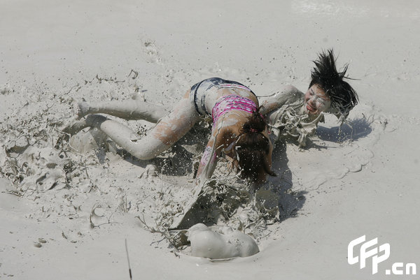 Two females are entangled in dogfight during a distinctive Women's Mud Wrestling Match, as some 40 female contestants from both China and overseas take part in this very amusing sport with the skin-friendly slurry and mud from the deep sea, in Wuhan, central China's Hubei Province, May 3, 2009.[Xiong Bo/CFP]