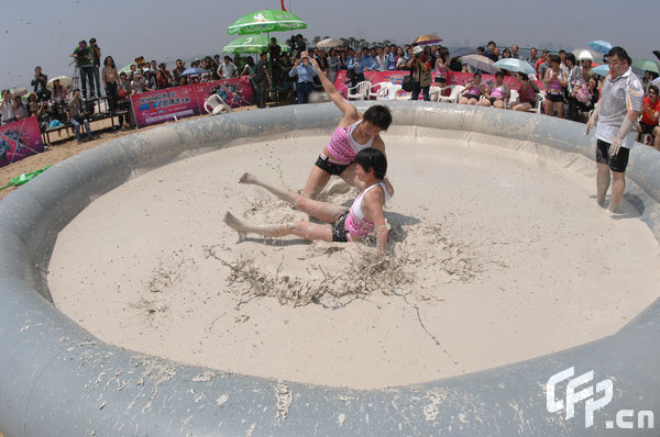 Two females are entangled in dogfight during a distinctive Women's Mud Wrestling Match, as some 40 female contestants from both China and overseas take part in this very amusing sport with the skin-friendly slurry and mud from the deep sea, in Wuhan, central China's Hubei Province, May 3, 2009.[Xiong Bo/CFP]