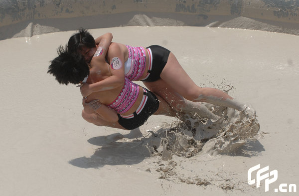 Two females are entangled in dogfight during a distinctive Women's Mud Wrestling Match, as some 40 female contestants from both China and overseas take part in this very amusing sport with the skin-friendly slurry and mud from the deep sea, in Wuhan, central China's Hubei Province, May 3, 2009.[Xiong Bo/CFP]